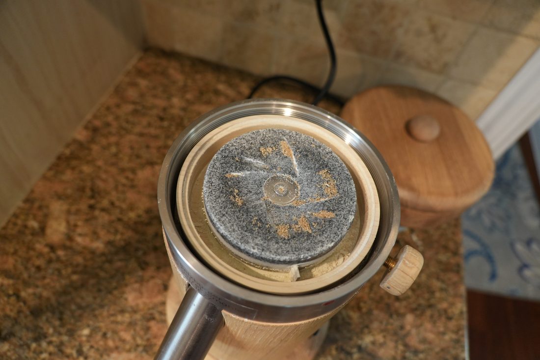 Top-down view of the granite grinding stone inside a Salzburg grain mill, dusted with fresh flour